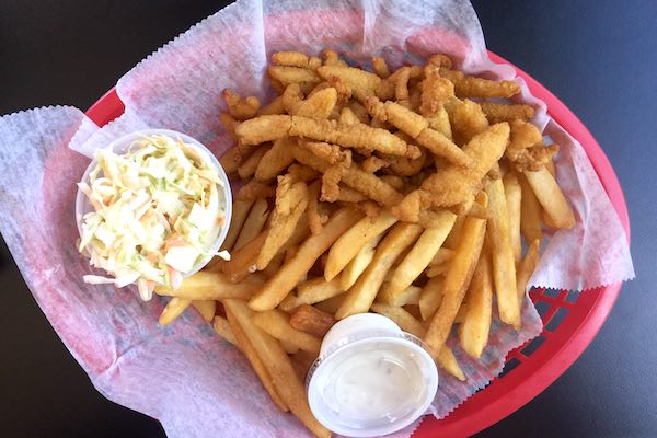 A basket of clam strips with fries and slaw.