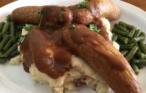 Sausage and mash potatoes with gravy, served with green beans. This is called Bangers 'N' Mash.