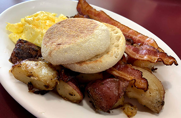 English muffin with scrambled eggs, bacon, home fries.