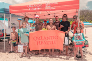 Orlando Health volunteers and members of Sober Surfers engaged with community members at the Orlando Health tent during the Longest Day, Longest Ride Surf Contest at Sebastian Inlet, hosted by the Sebastian Chamber of Commerce and held at Sebastian Inlet on Sunday, June 21. Orlando Health sponsored nine Sober Surfers participants in the contest, where surfer Brad Lee (pictured, fourth from left) won first place. Orlando Health team member Victor Rodriguez served as a judge, while additional team members distributed sunscreen and beach balls and raffled off a boombox and beach chairs. The family-friendly event raised funds and awareness for Alzheimer’s disease.